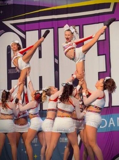 A group of cheerleaders are performing in front of a sign that says cheer