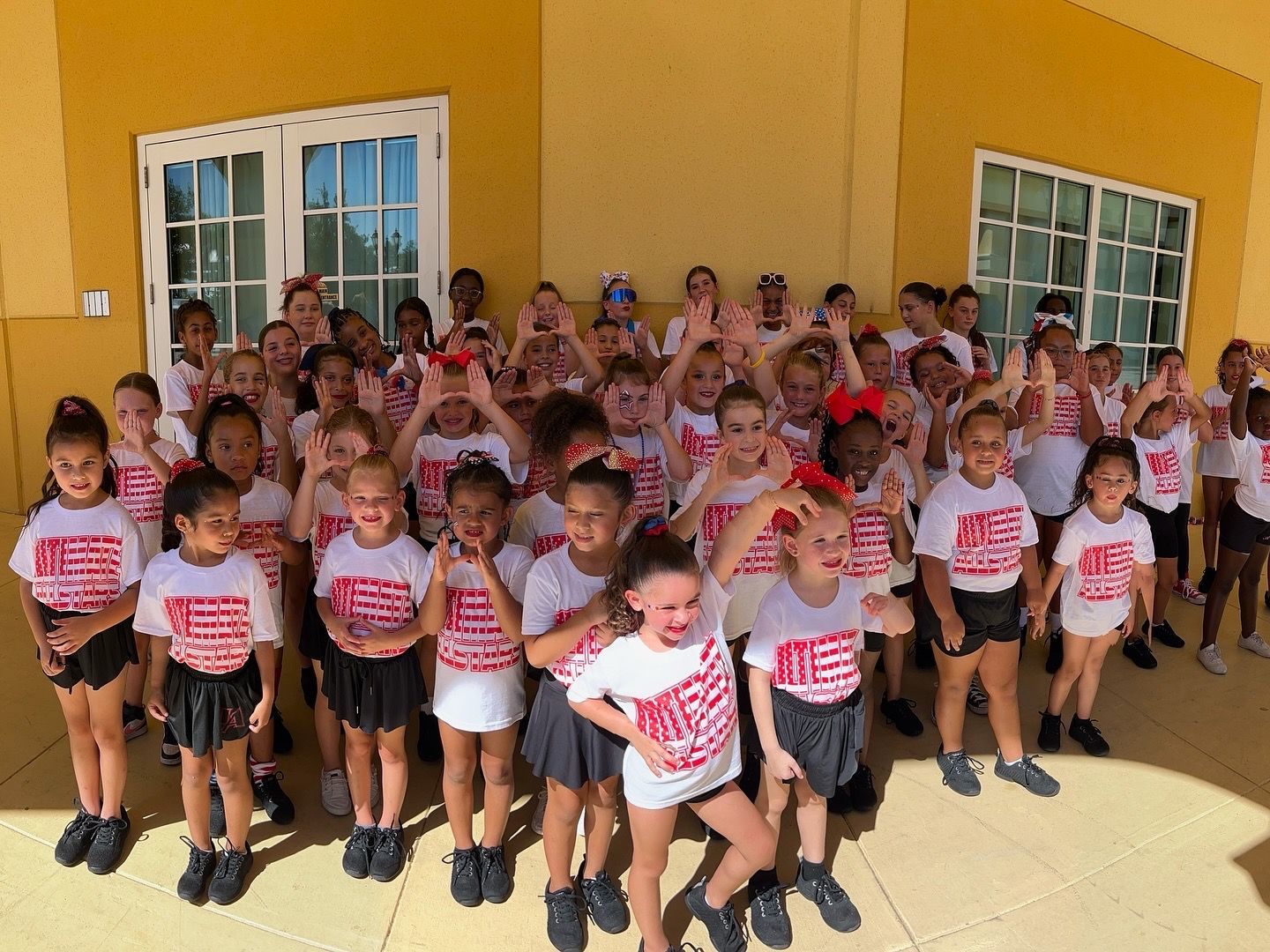 A large group of children are posing for a picture in front of a building.