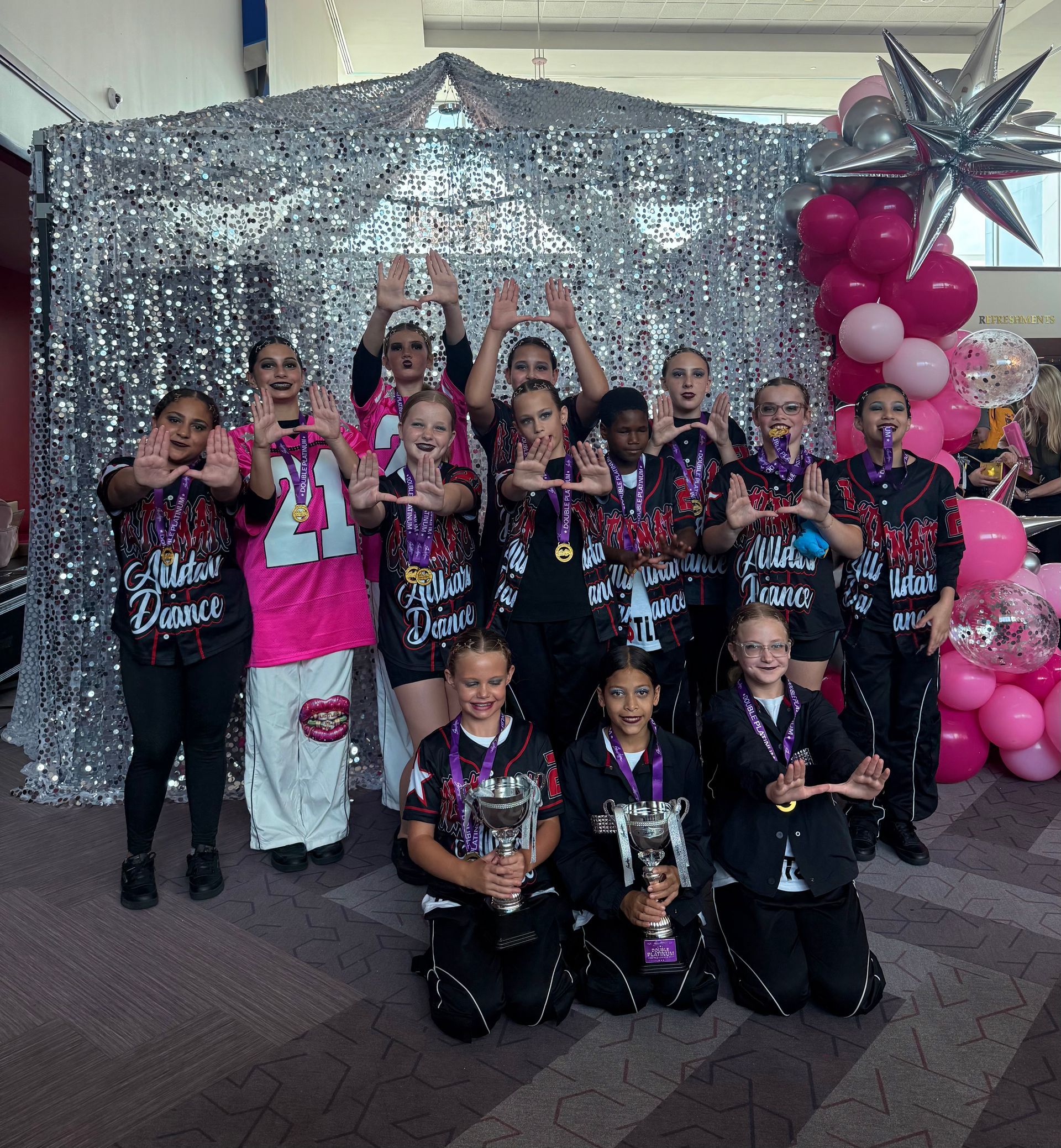 A group of children are posing for a picture in front of a sequined wall.