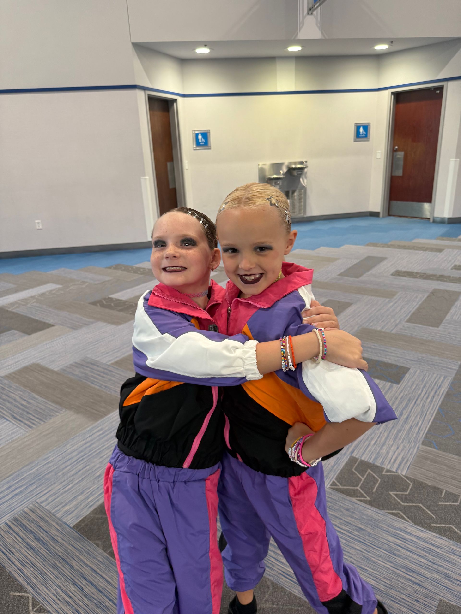 Two little girls are hugging each other in a room