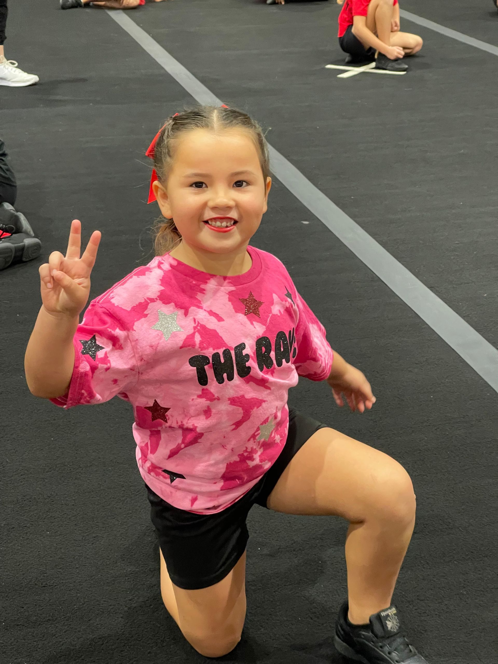 A little girl wearing a pink tie dye shirt with the word thera on it