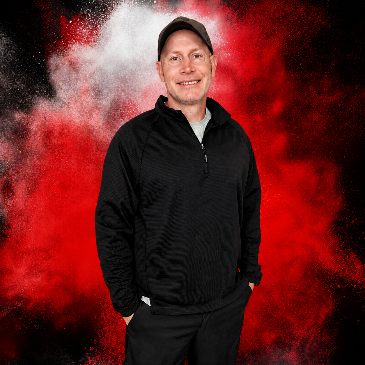 A man in a black shirt and shorts is standing in front of a red door