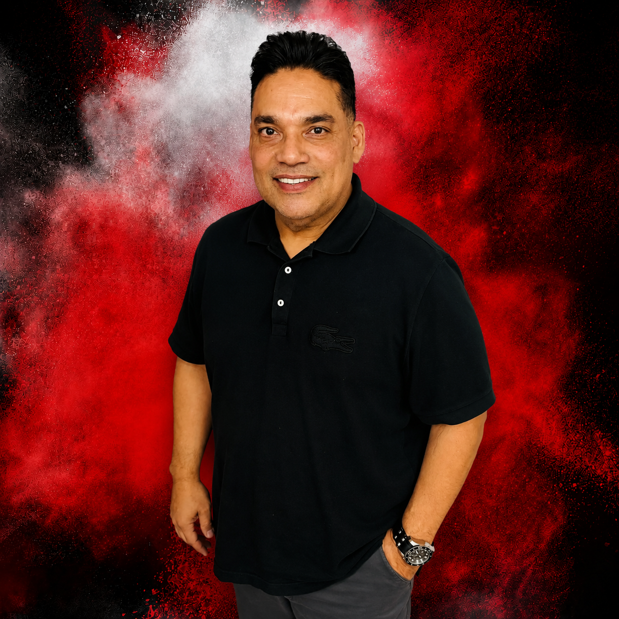 A man in a black shirt is standing in front of a red door.