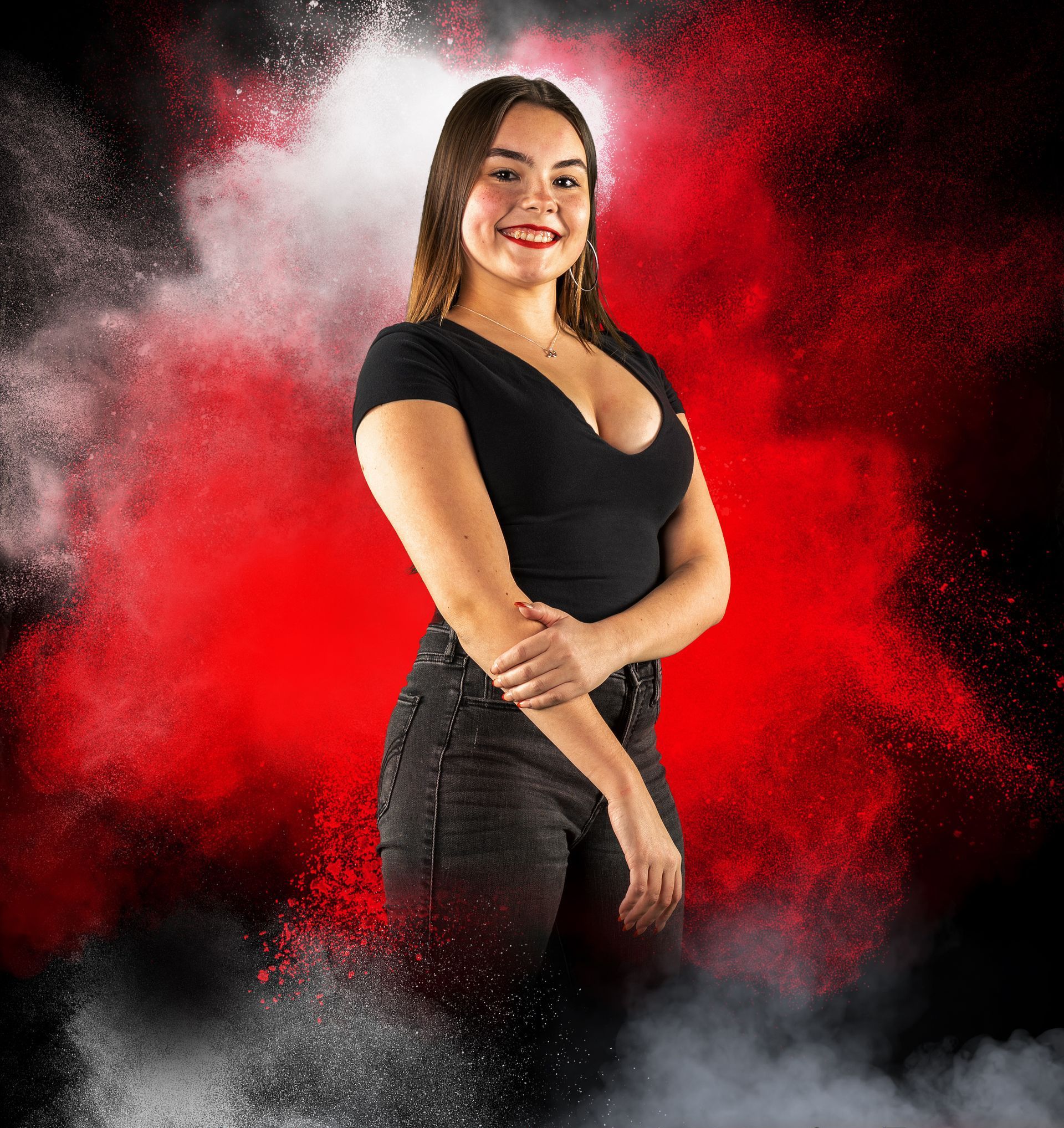 A woman in a black top is standing in front of a red background.