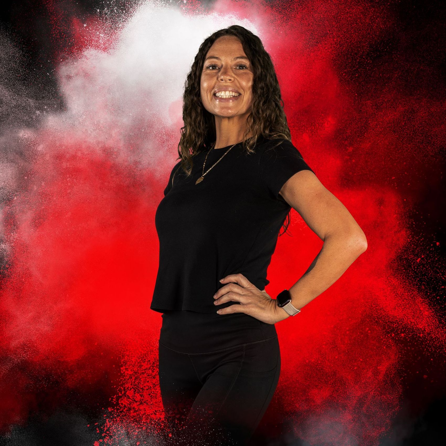 A woman in a black shirt is standing in front of a red background.