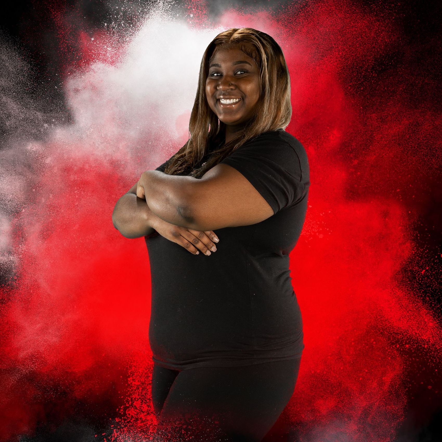A woman in a black shirt is standing with her arms crossed in front of a red background.