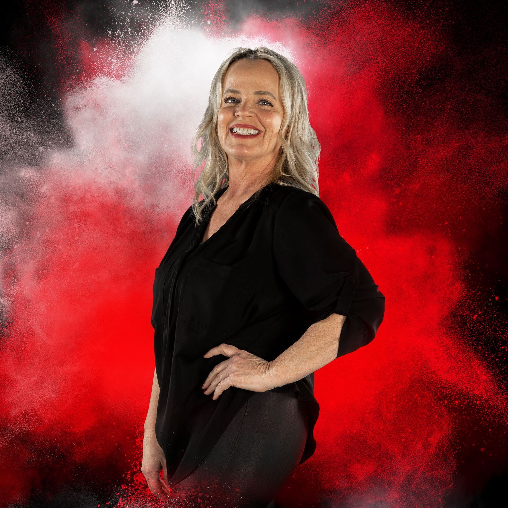 A woman in a black shirt is standing in front of a red background.