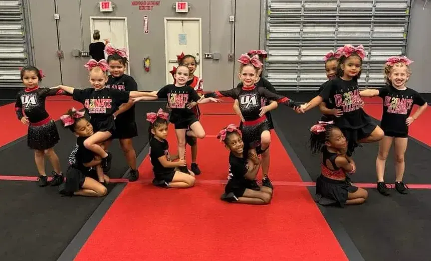 A group of cheerleaders are posing for a picture on a red carpet.