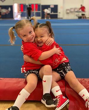 Two little girls are hugging each other in a gym.