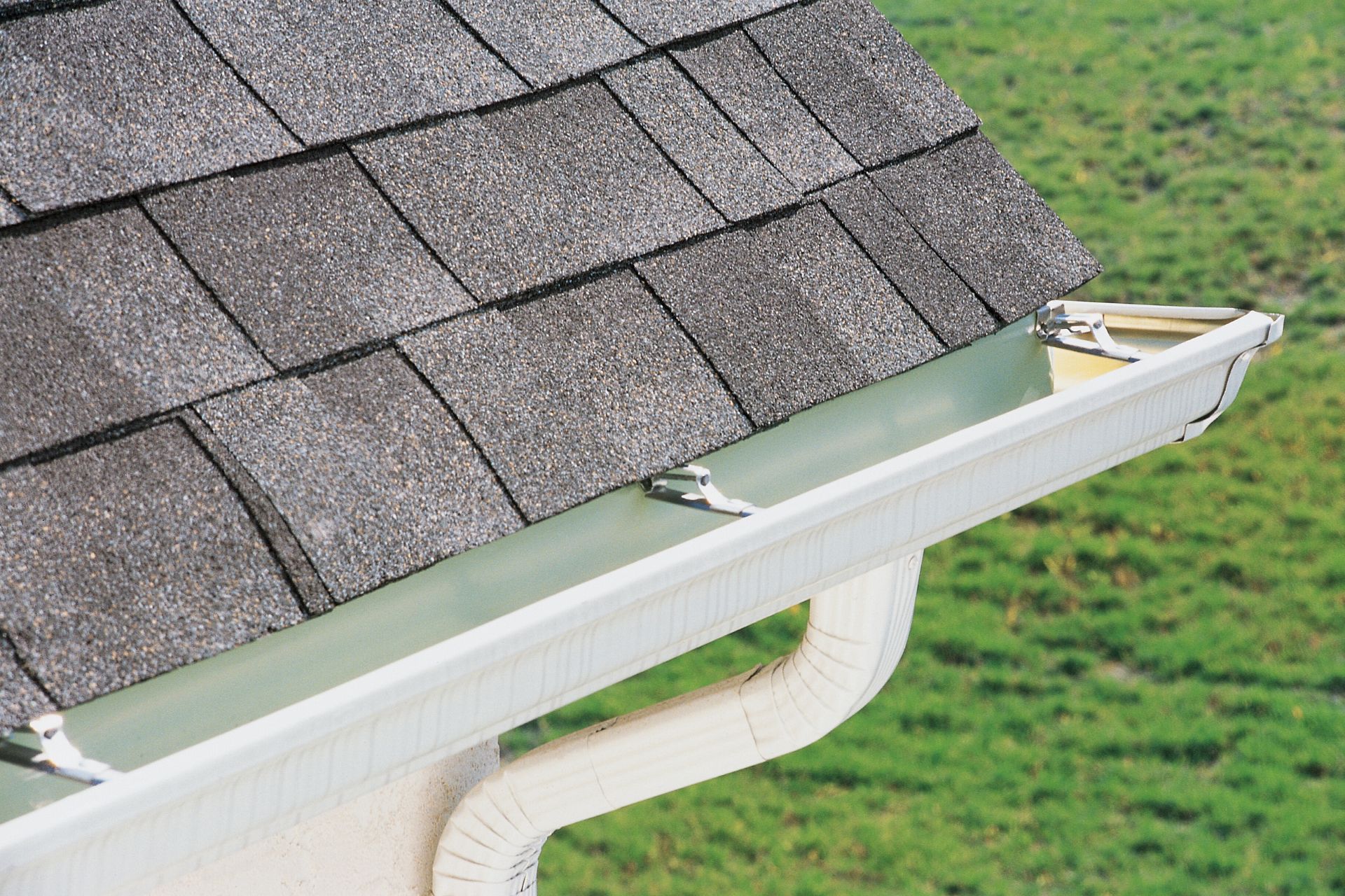 A close up of a brightened gutter with a roof in the background