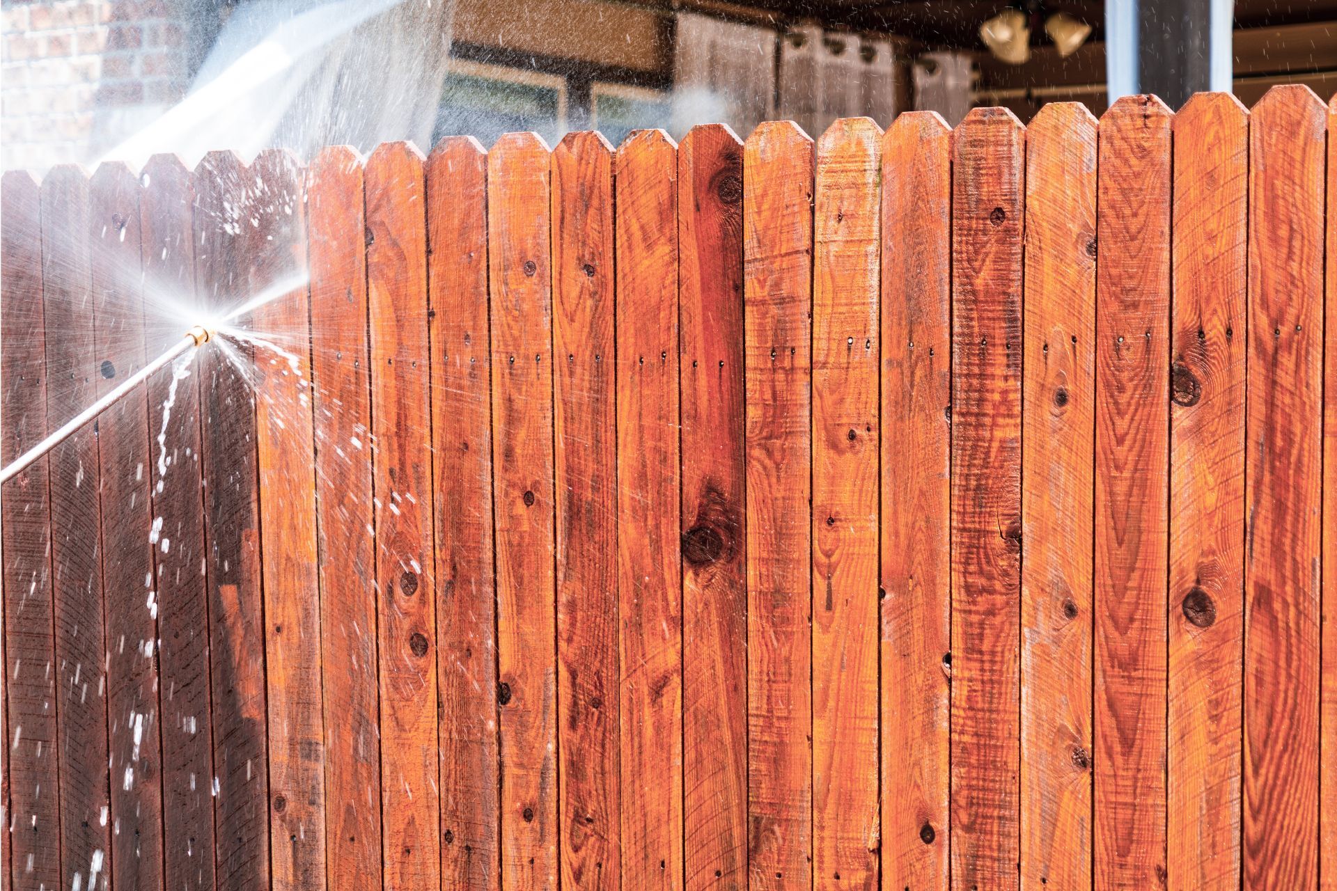 A wooden fence is being cleaned with a pressure washer.
