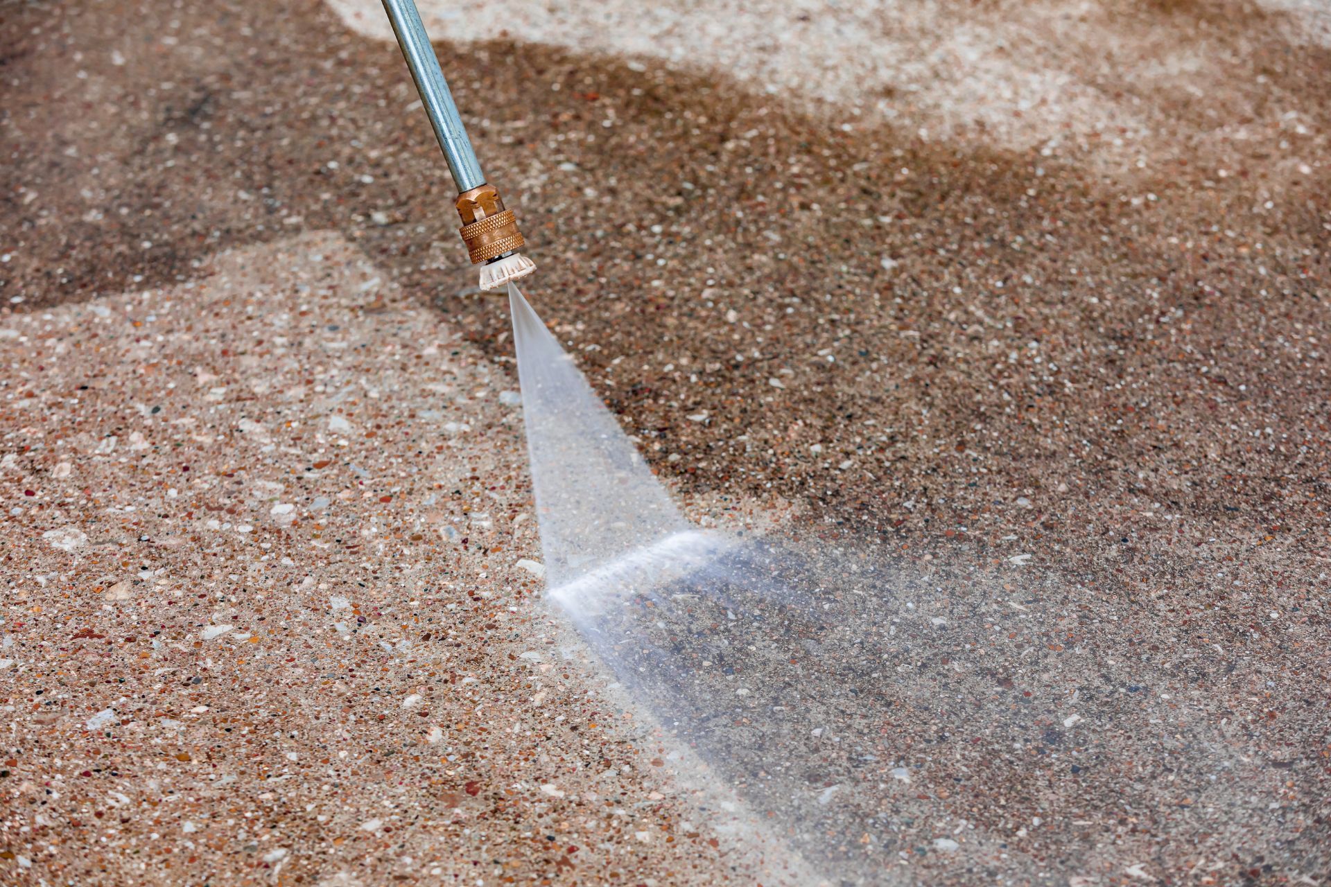 A person is using a high pressure washer to clean a concrete floor.