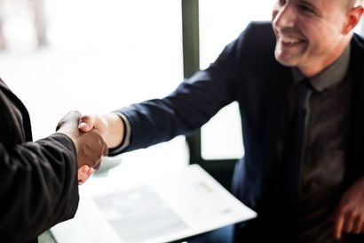 Two people shaking hands, one smiling. Agreement or deal.