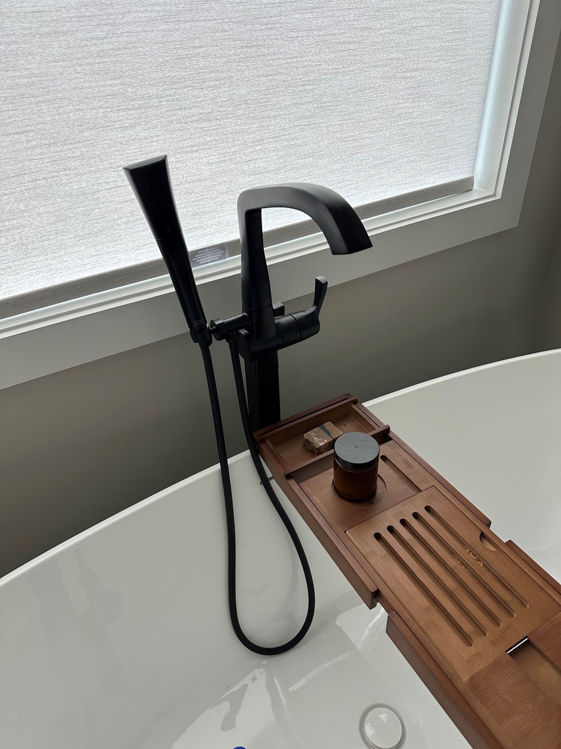 A bathtub with a black faucet and a wooden bathtub tray.  - Hendersonville, TN - Chris' Plumbing Service & Repair