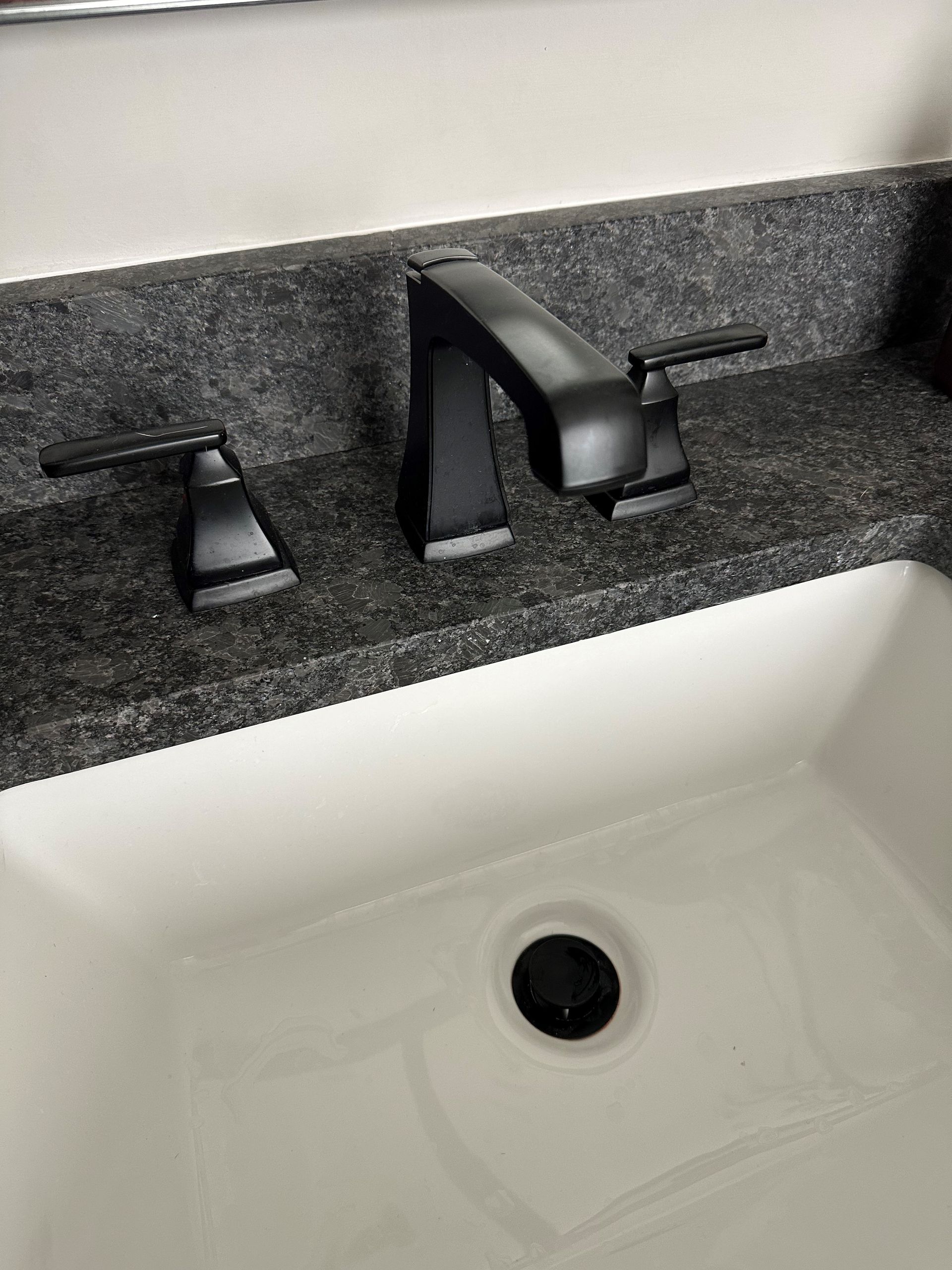 A bathroom sink with a black faucet and granite counter top. - Hendersonville, TN - Chris' Plumbing Service & Repair