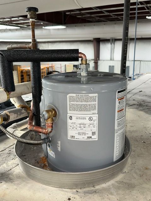 A water heater is sitting on top of a metal tray. A water heater is sitting on top of a metal tray.