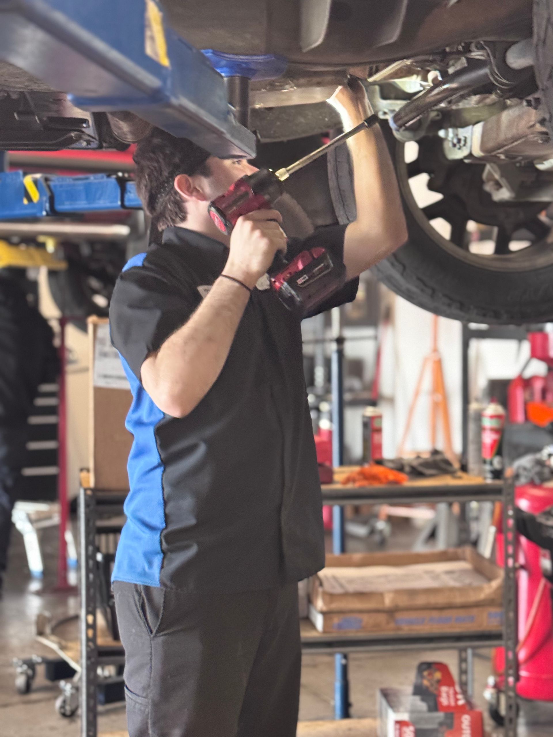 A man is working on the underside of a car in a garage.