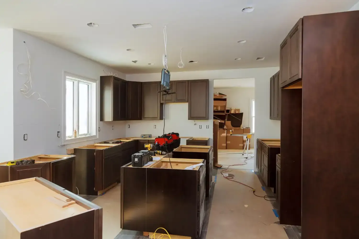 Kitchen under construction with dark brown cabinets, unfinished walls, and equipment.