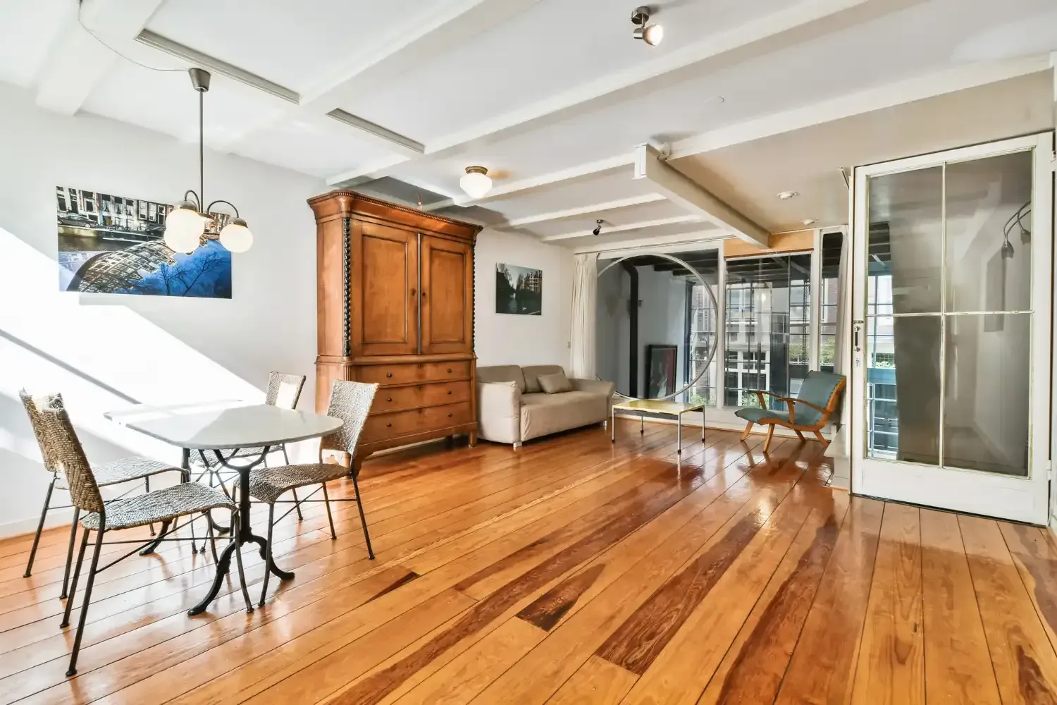 Living room with wooden floors, antique cabinet, and glass doors leading to balcony.