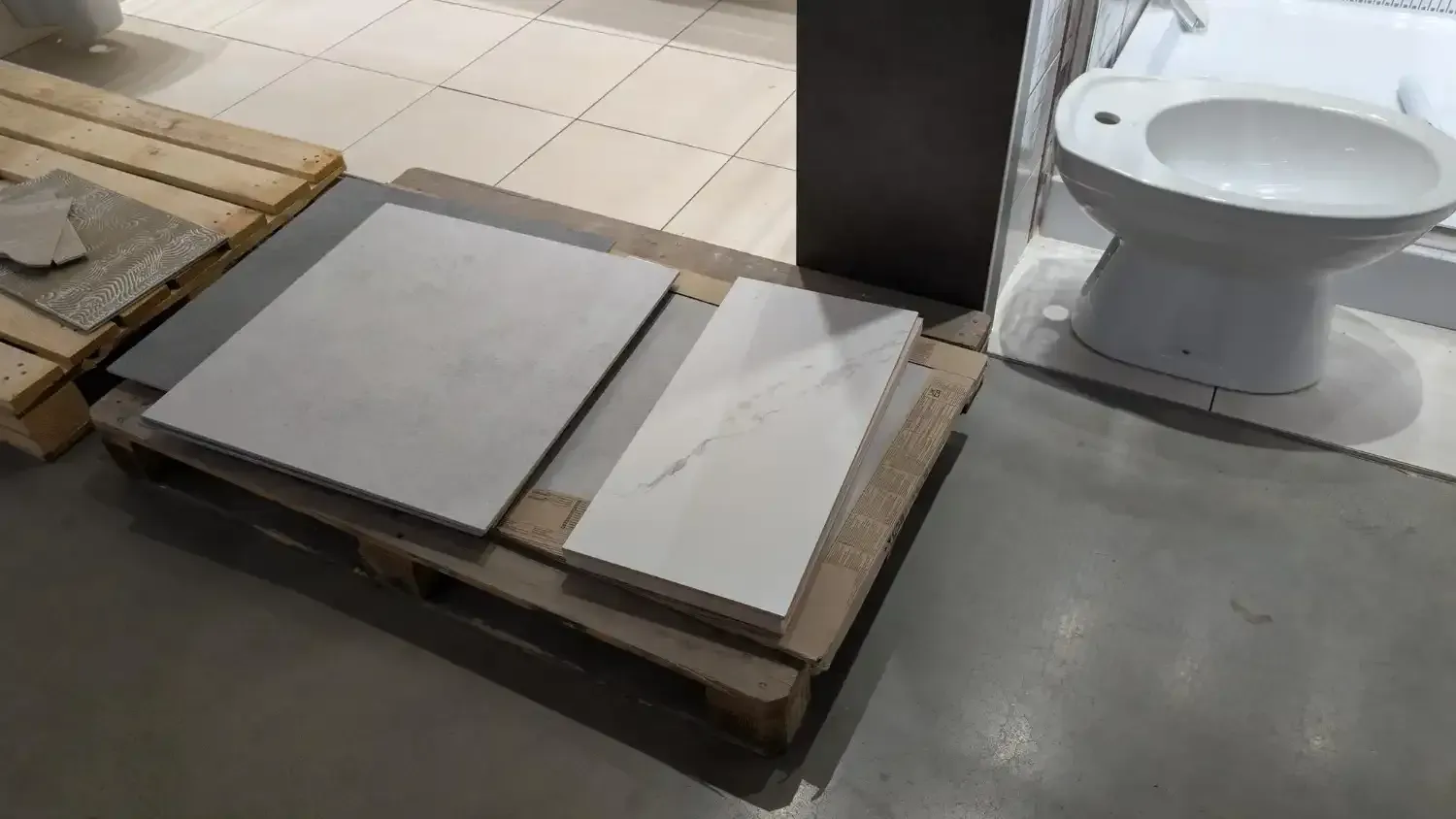 Tiles on a pallet, beside a toilet, in a showroom.
