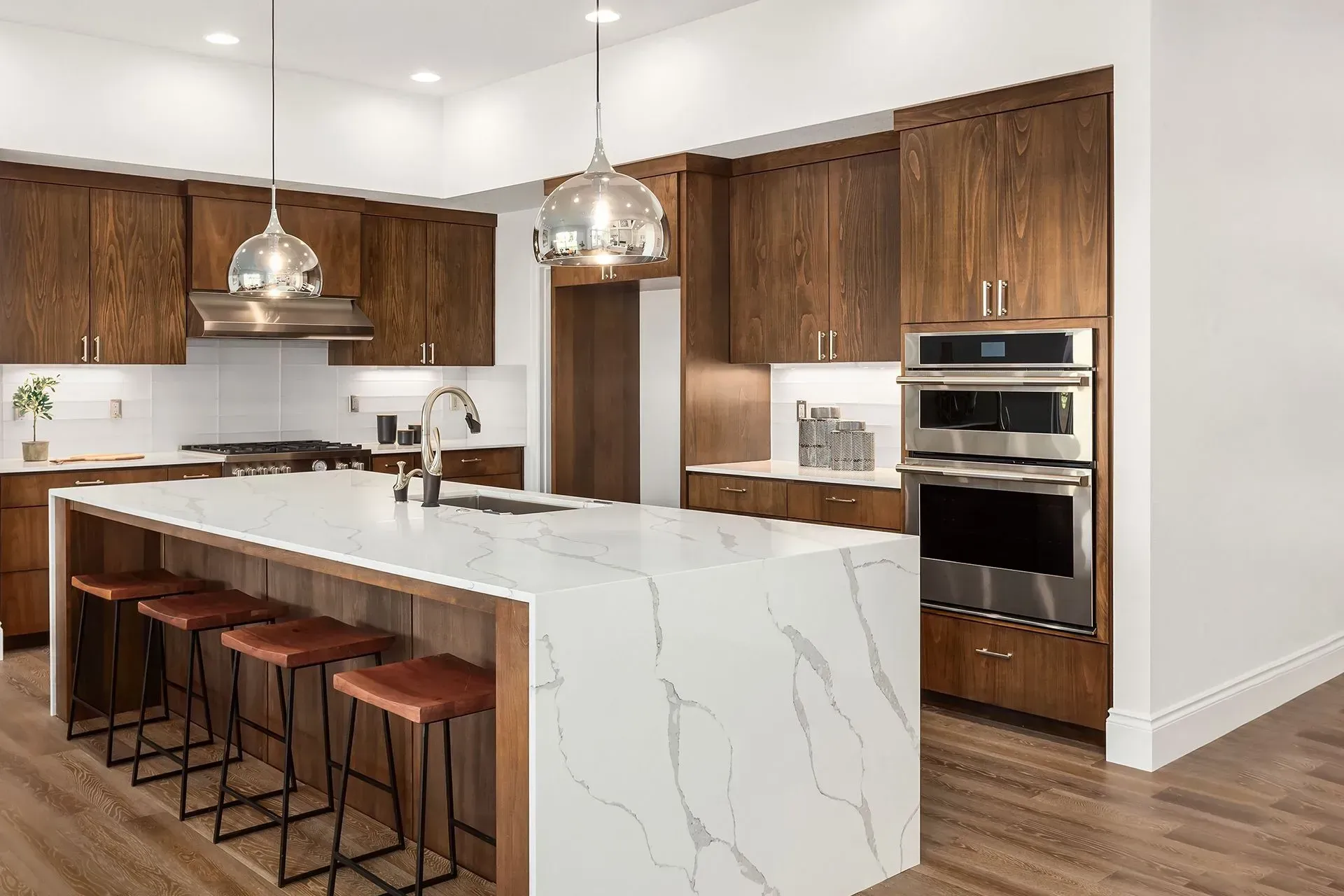 Modern kitchen with dark wood cabinets, white marble island, and stainless steel appliances.