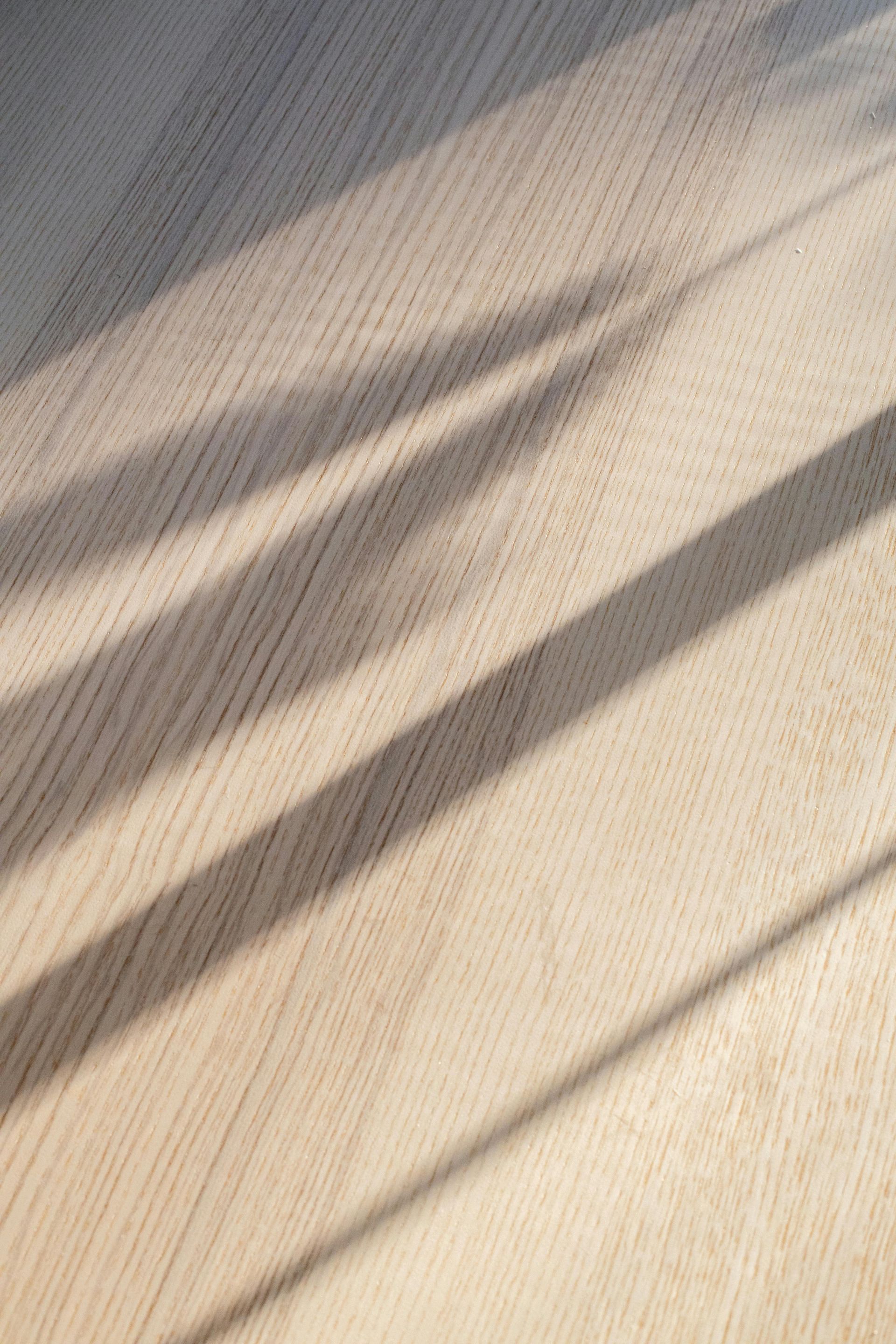 Wooden surface with long, angled shadows across the grain.