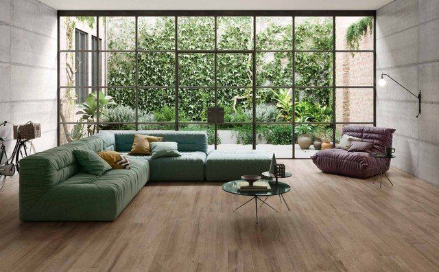 salotto con pavimento in ceramica effetto legno e divano verde