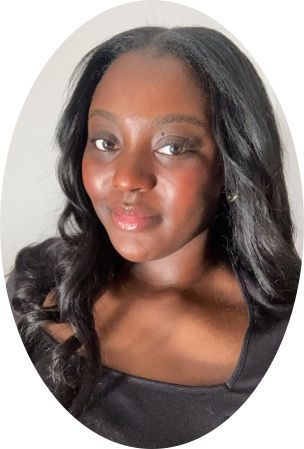 Woman with long, wavy dark hair smiling, wearing a black top against a light background.