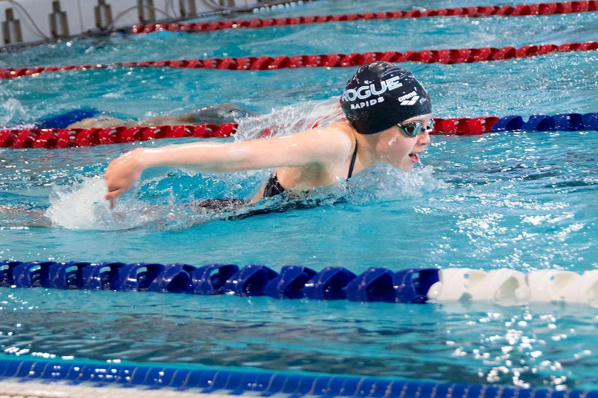 A woman is swimming in a pool wearing a doline swim cap.