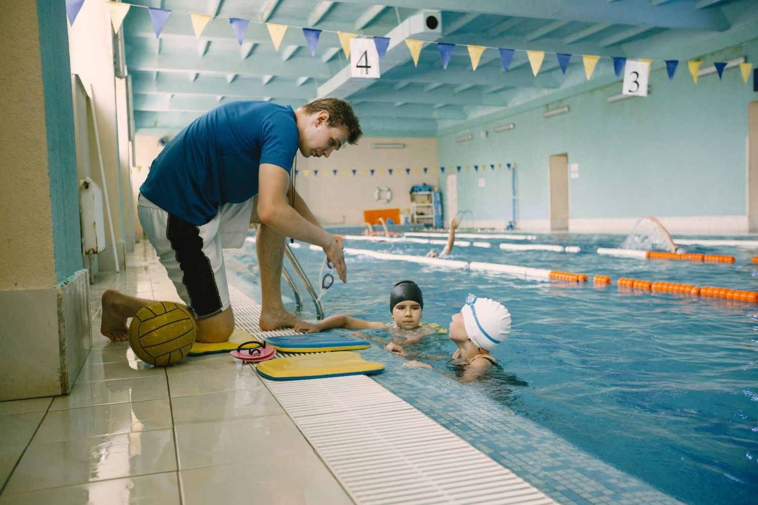 A man is teaching a group of children how to swim in a swimming pool.