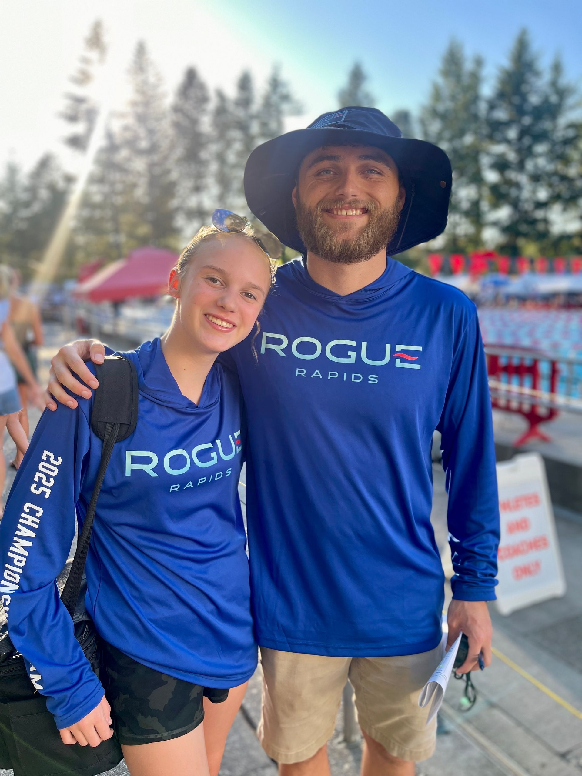 a boy and a girl are standing next to each other in front of a pool wearing arena swimsuits