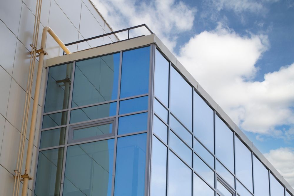Modern Building Corner With Reflective Blue Glass Windows — Awesome Window Tint In Taree, NSW