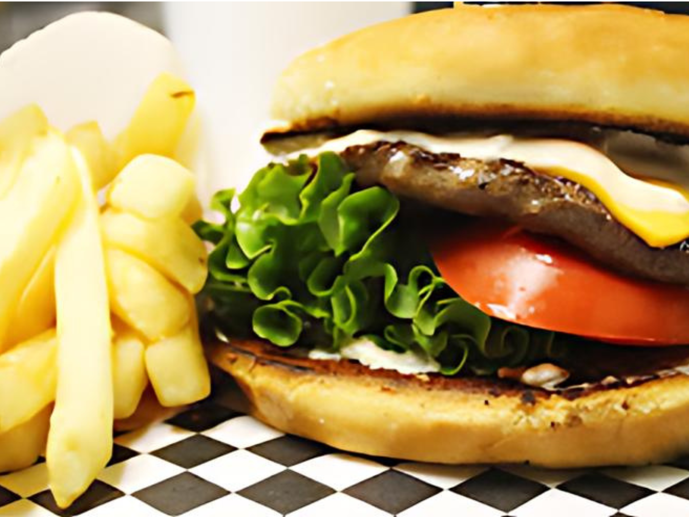 A hamburger and french fries on a checkered table cloth