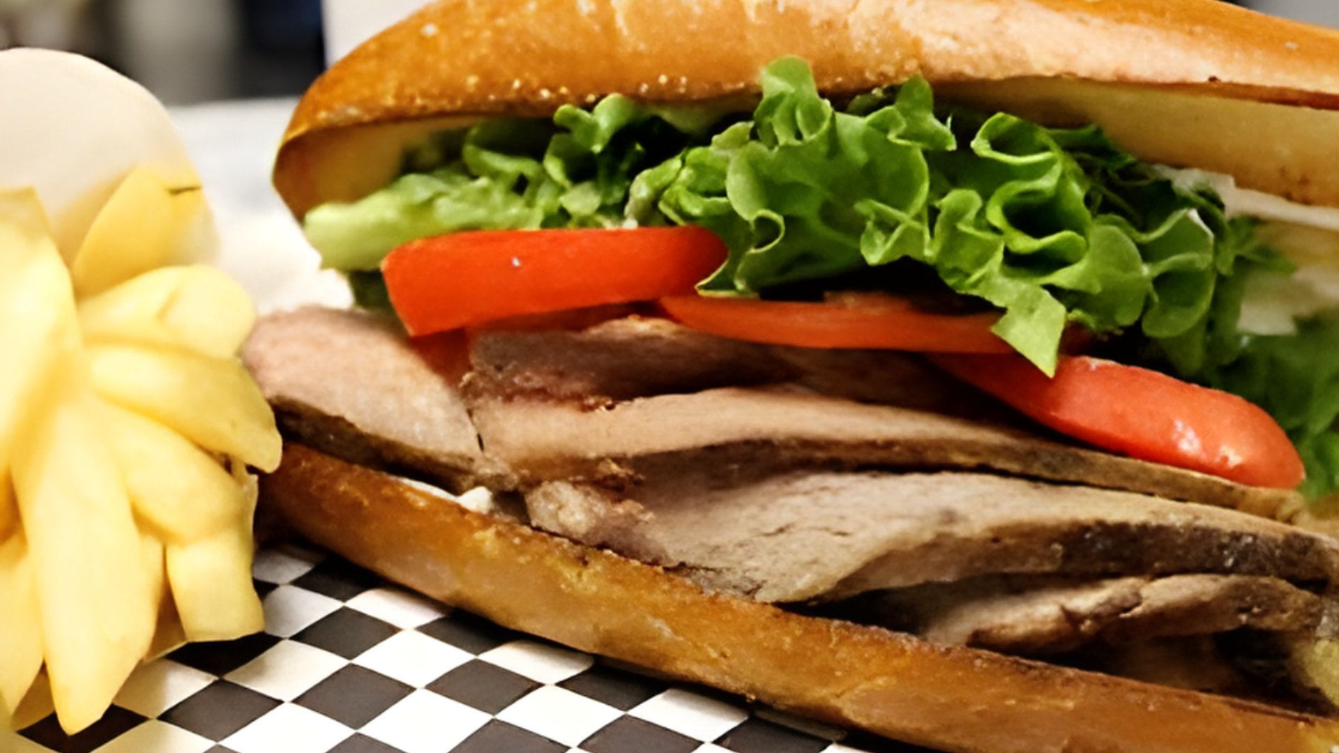 A sandwich and french fries on a checkered table cloth