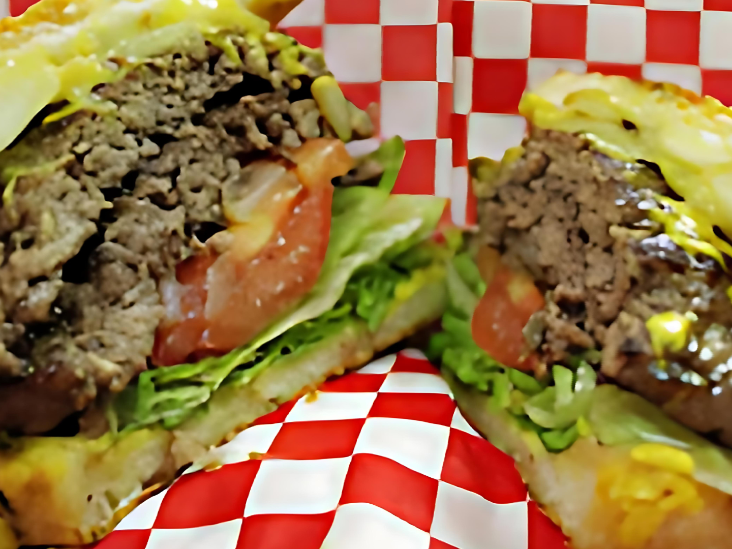 A hamburger is cut in half on a checkered paper