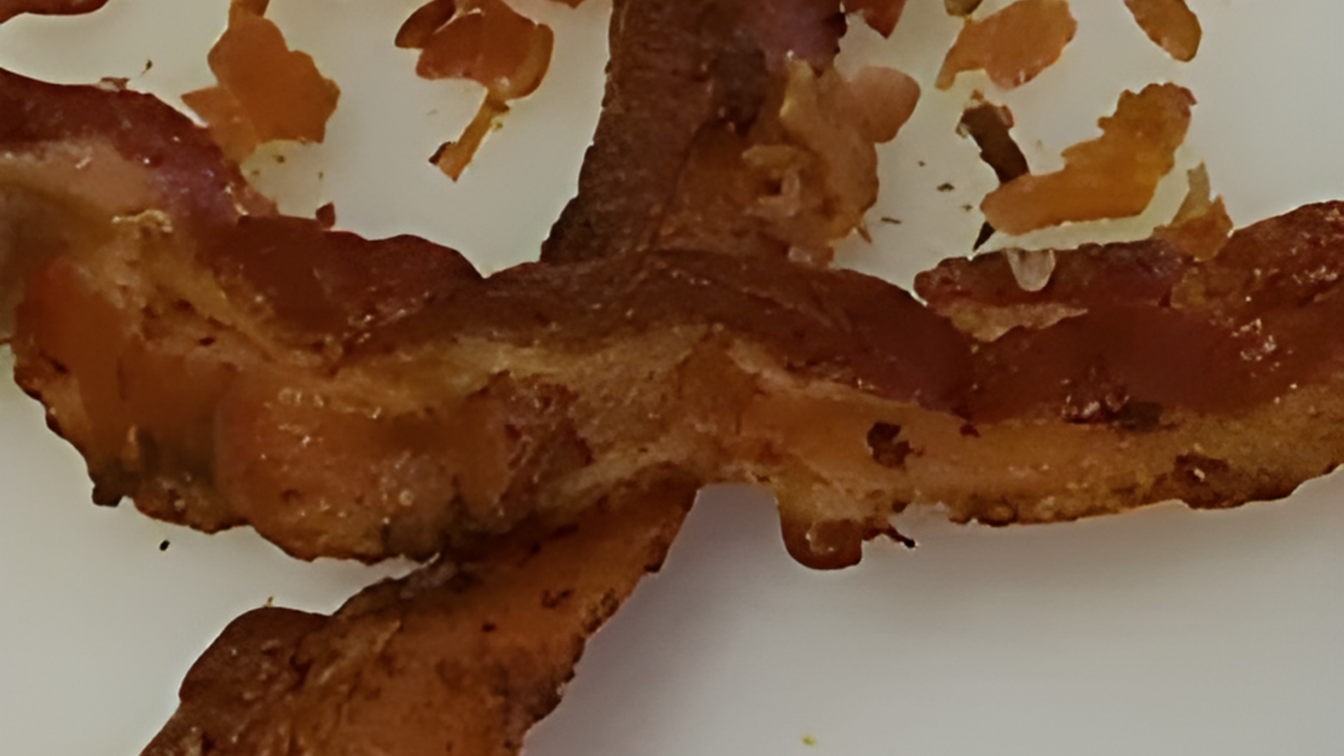 A close up of a piece of bacon on a white plate