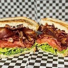 A close up of a sandwich cut in half on a checkered table cloth.