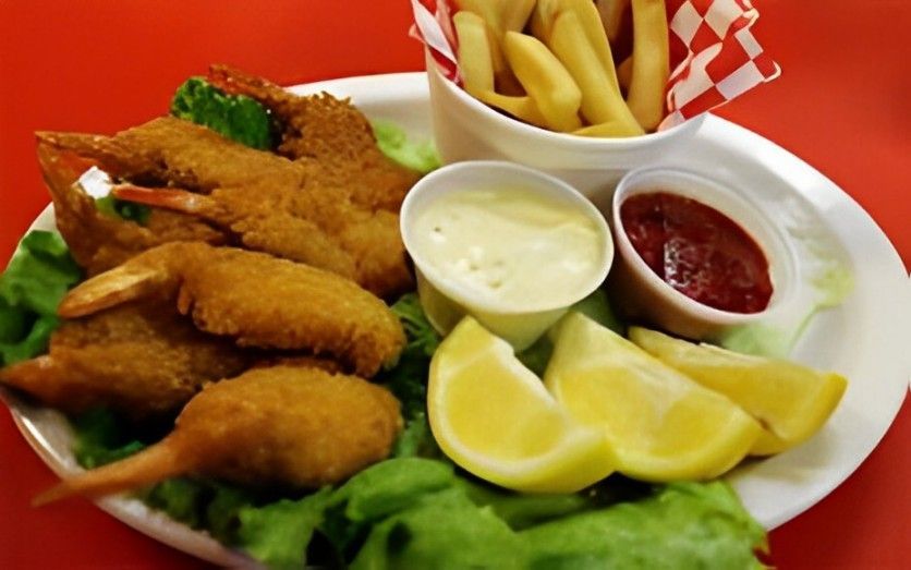 A plate of fried shrimp and french fries on a red table