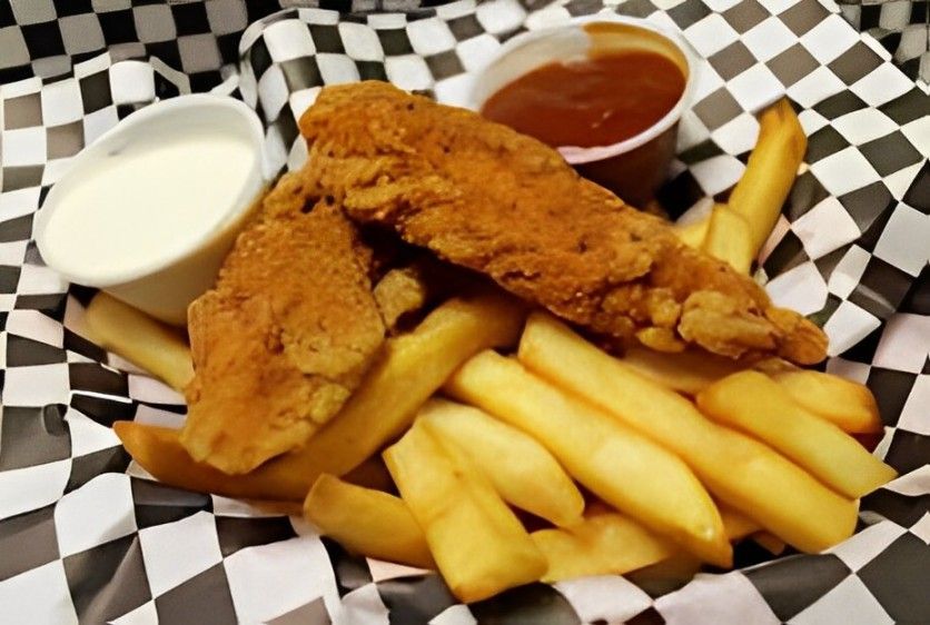 A basket of fried chicken and french fries with dipping sauce