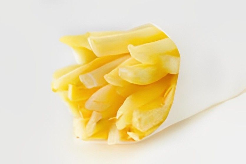 A paper cone filled with french fries on a white surface