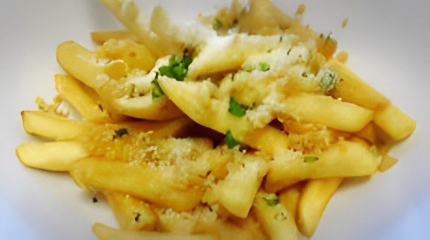 A white plate topped with french fries and cheese