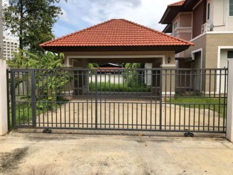 A Black Metal Gate in Front of a Driveway Leading to a Carport With a Red-tiled Roof — Fencer Steve In Crescent Head, NSW