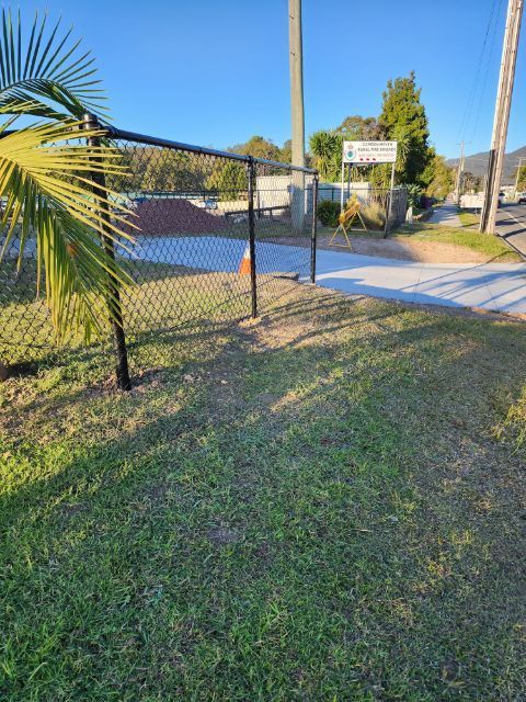 Black Chain-link Fence and Gate Leading to a Building, Grass in the Foreground, Blue Sky — Fencer Steve In Hat Head, NSW