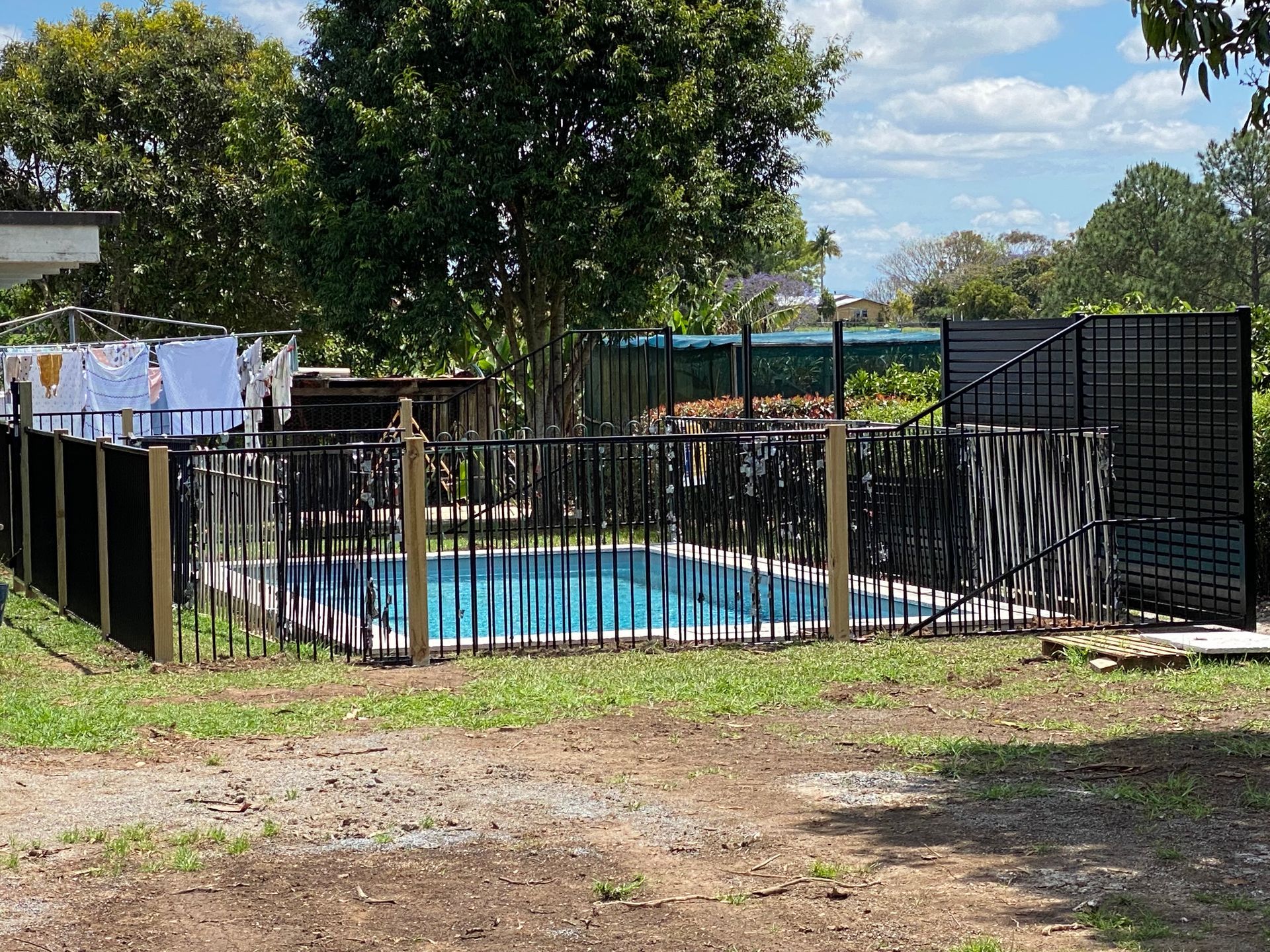 Pool with a black fence in an outdoor setting, with trees and sky in the background — Fencer Steve In Temagog, NSW
