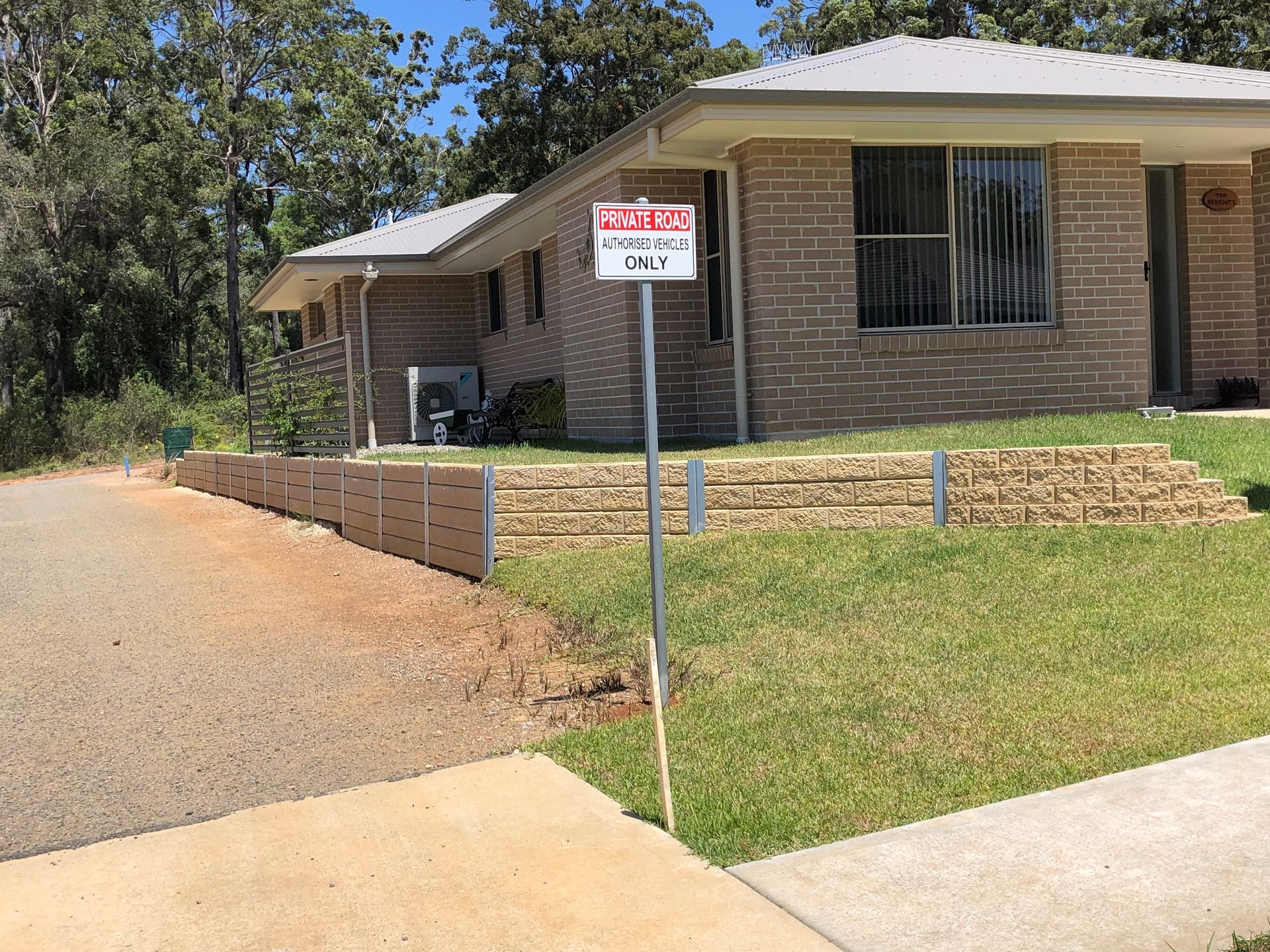 Signpost in Front of Brick Duplex With Retaining Wall and Green Grass — Fencer Steve In Temagog, NSW