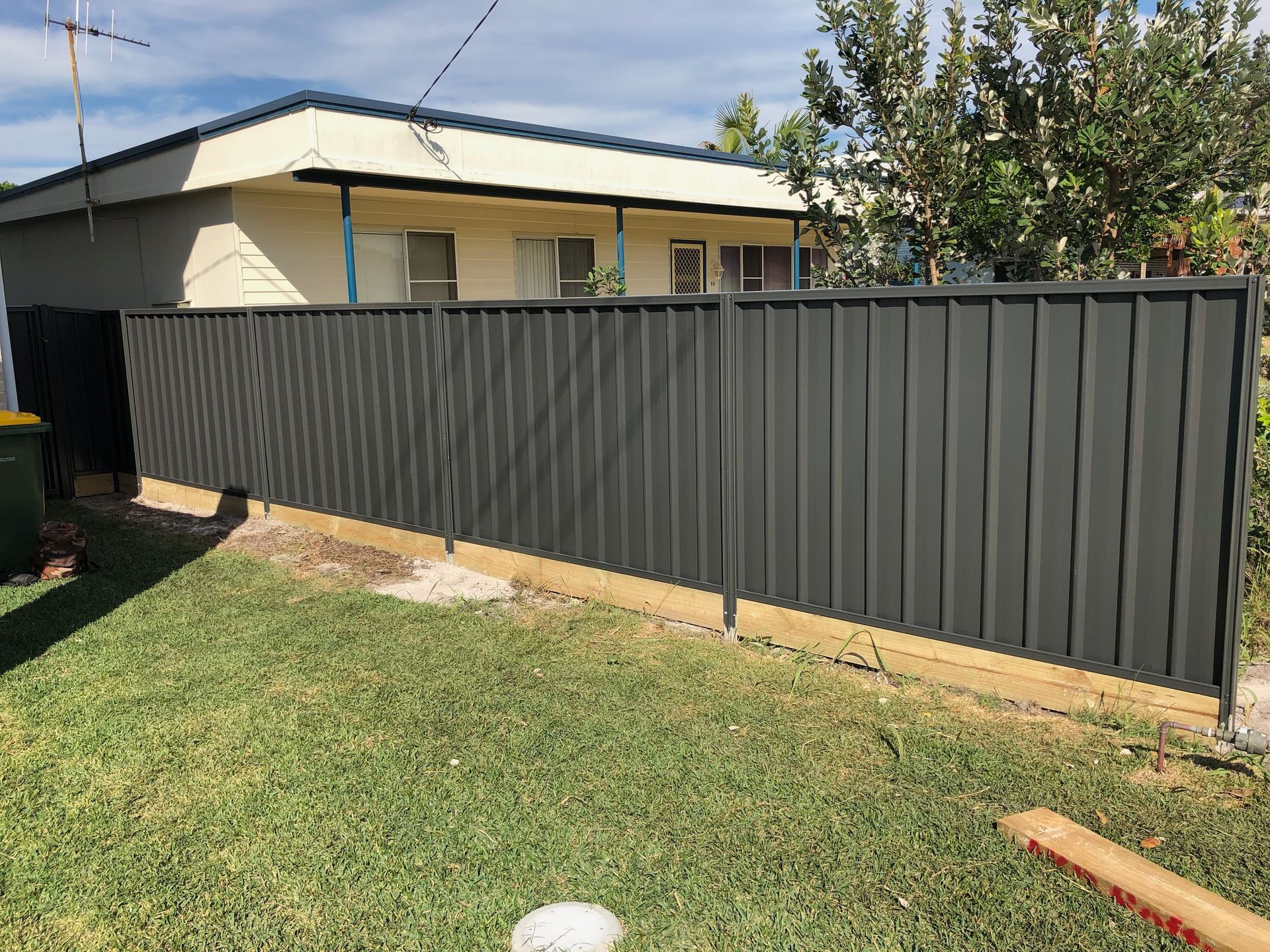 Gray vertical-slat fence in front of a beige house on a grassy lawn — Fencer Steve In Temagog, NSW