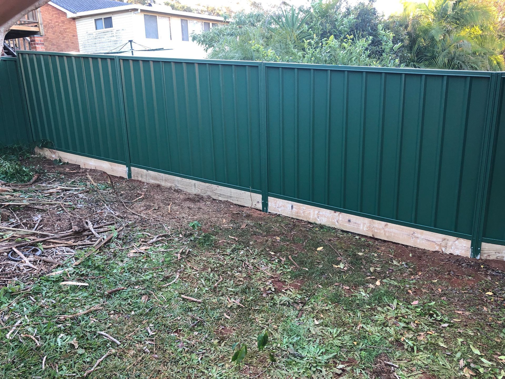 Green metal fence in a backyard, set against a house and foliage — Fencer Steve In Temagog, NSW