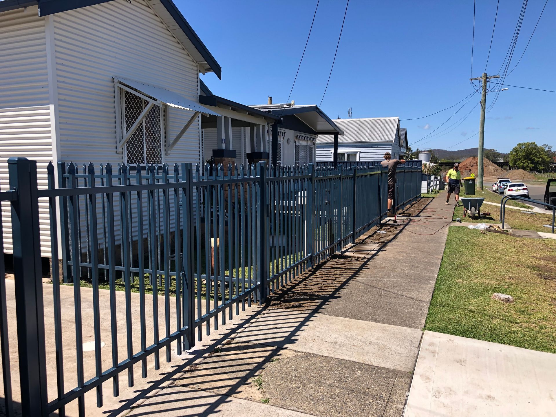 Blue fence along a sidewalk in front of a white house on a sunny day — Fencer Steve In Temagog, NSW