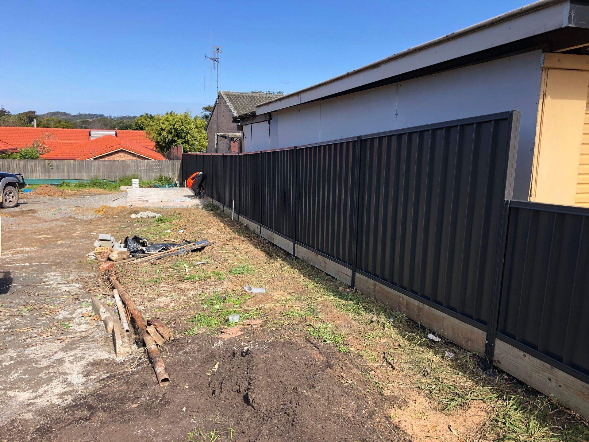 Black Corrugated Metal Fence Bordering a House and Yard on a Sunny Day — Fencer Steve In Wauchope, NSW