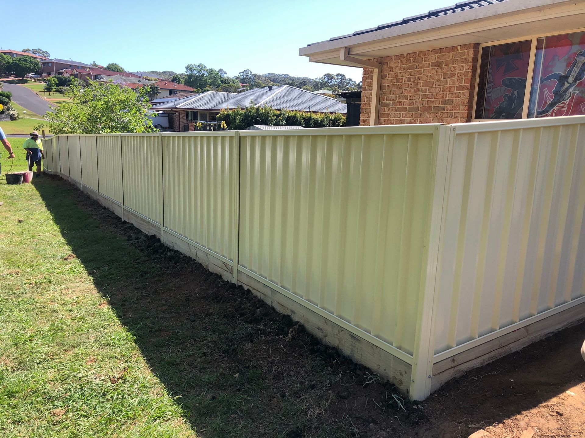 Tan Corrugated Metal Fence Bordering a Yard With Grass — Fencer Steve In Temagog, NSW